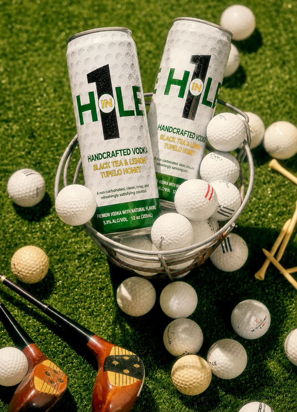 Hole in 1 cans in a range ball bucket on turf.